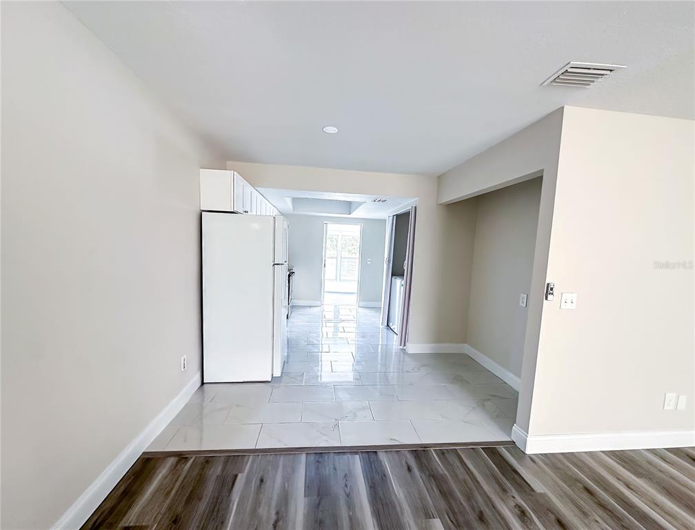 A kitchen with white cabinets and appliances features light tile flooring and a doorway — 15 W COUNTRY COVE, KISSIMMEE, FL