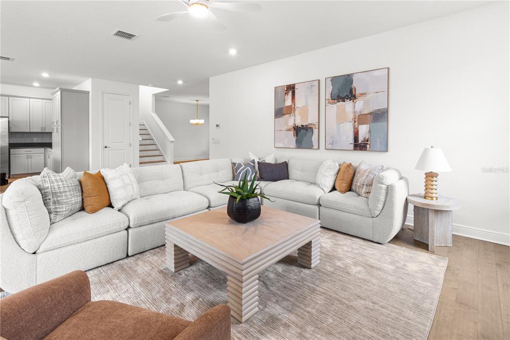 A living room features a large sectional sofa, a square coffee table, and abstract wall art — 4421 W BAY COURT AVENUE, TAMPA, FL