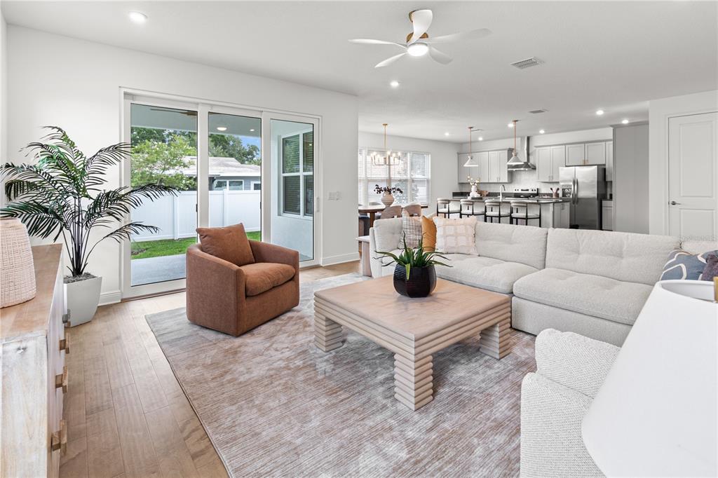 A living room with a sectional sofa, coffee table, and sliding doors leading to a yard — 4421 W BAY COURT AVENUE, TAMPA, FL