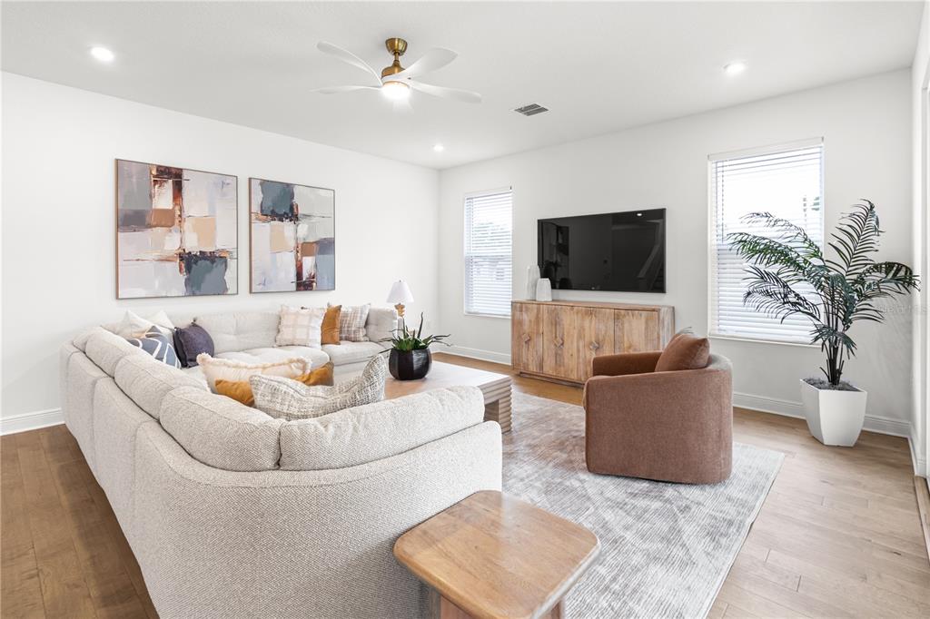 A living room features a large sectional sofa, a brown armchair, and a television console — 4421 W BAY COURT AVENUE, TAMPA, FL