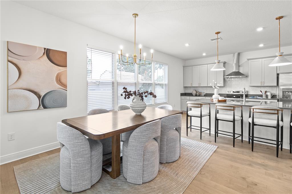 A dining area with a wooden table and gray chairs sits adjacent to a modern kitchen — 4421 W BAY COURT AVENUE, TAMPA, FL