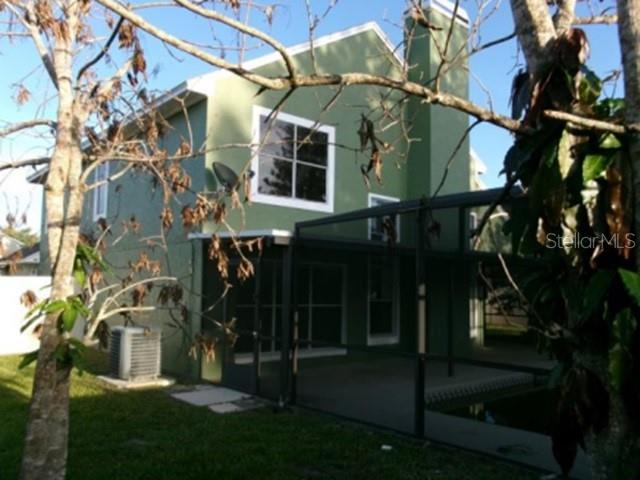 The exterior of a two-story green house features a screened-in patio and a central chimney — 3298 AMACA CIRCLE, ORLANDO, FL