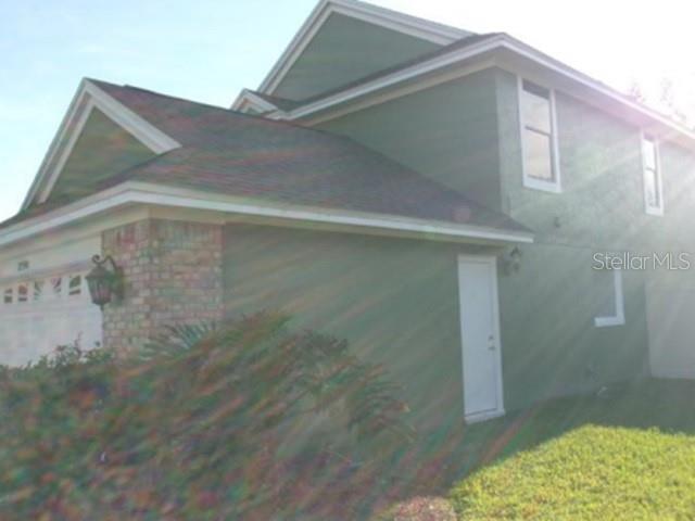A two-story house with green stucco siding, a brick-accented garage, and a side entry door — 3298 AMACA CIRCLE, ORLANDO, FL