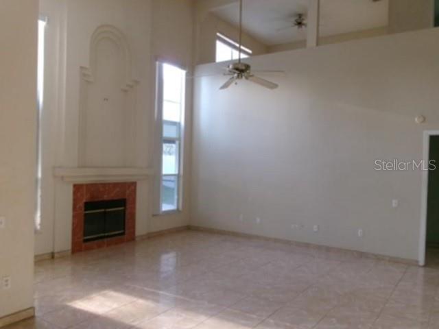 A spacious living room features tile flooring, a fireplace, and a high ceiling with fans — 3298 AMACA CIRCLE, ORLANDO, FL