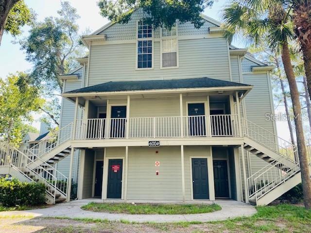 A two-story apartment building with light green siding, exterior staircases, and a covered balcony — 6004 WESTGATE DRIVE UNIT 104, ORLANDO, FL
