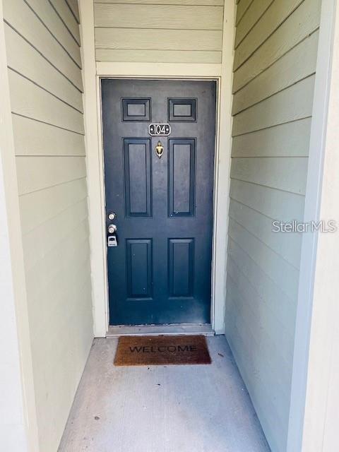 A dark blue front door with the number 104 is set in a recessed entryway — 6004 WESTGATE DRIVE UNIT 104, ORLANDO, FL