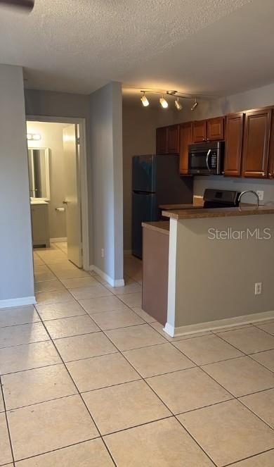 A kitchen with wood cabinets and tile flooring opens to a hallway leading to a bathroom — 6004 WESTGATE DRIVE UNIT 104, ORLANDO, FL