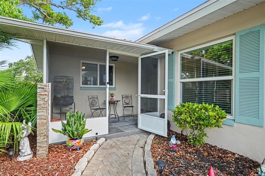 A brick walkway leads to a screened-in porch with a metal table and two chairs — 5603 LOWN STREET N, ST PETERSBURG, FL