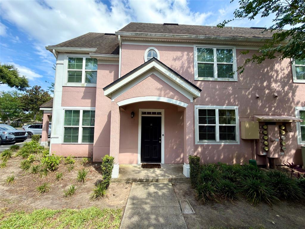 A two-story pink stucco townhouse with a black front door and a covered entryway — 3420 GREENWICH VILLAGE BOULEVARD UNIT 204, ORLANDO, FL