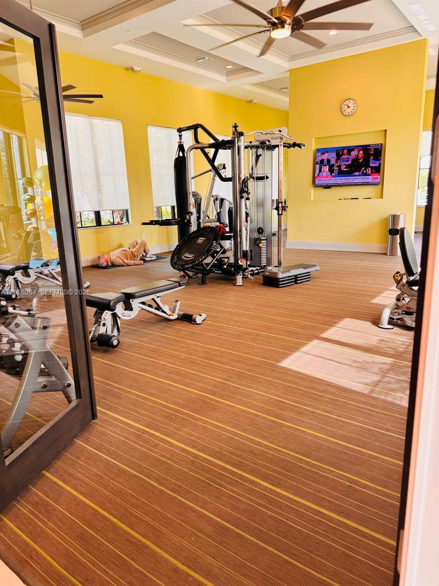 A gym with yellow walls, a multi-station weight machine, and a person exercising on a mat — 5811 CASSIDY LANE, Ave Maria FL 34142, AVE MARIA, FL
