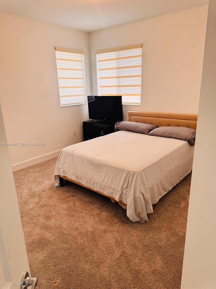 A bedroom features a bed with a patterned cover, a television on a stand, and windows — 5811 CASSIDY LANE, Ave Maria FL 34142, AVE MARIA, FL