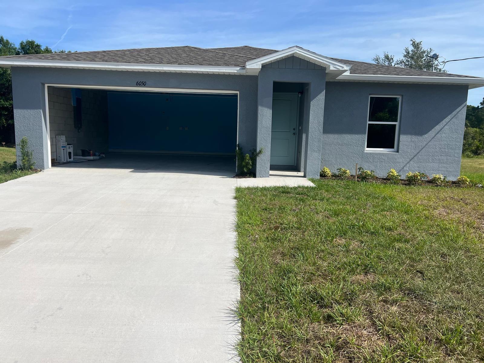 A single-story gray stucco house with a two-car garage and a front entrance — 6050 Pecan Circle, FL 33935, FL