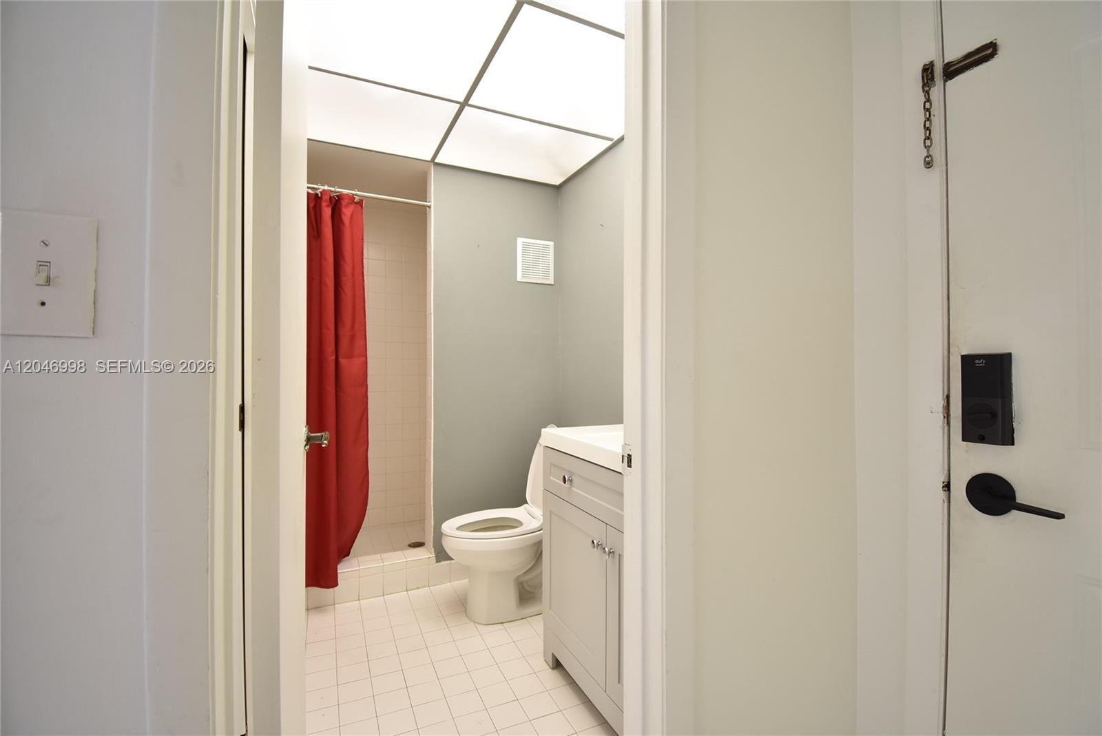 A small bathroom features a white vanity, a toilet, and a shower with a red curtain — 20741 NE 4th Ct # 104, Miami FL 33179, MIAMI, FL