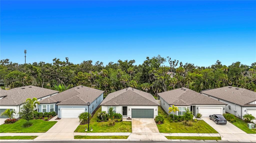 An exterior view of a row of single-story suburban houses with attached garages and lawns — 3125 61ST TERRACE E, ELLENTON, FL