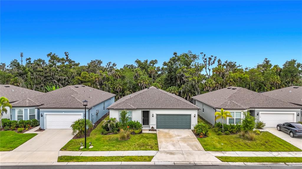 A row of three single-story suburban houses with gray roofs and attached garages — 3125 61ST TERRACE E, ELLENTON, FL