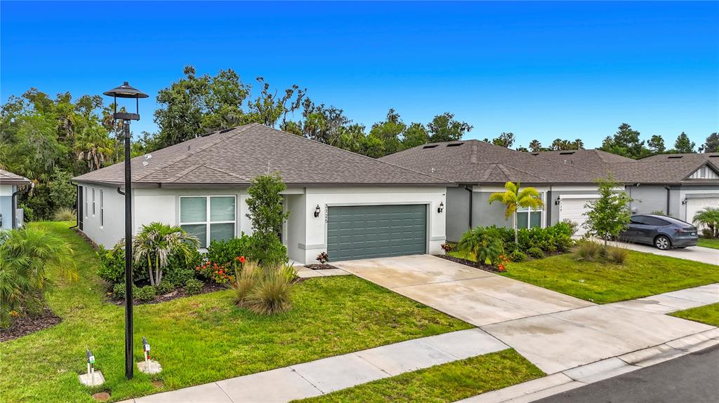 A single-story house with a gray garage, tan exterior, and a manicured front lawn — 3125 61ST TERRACE E, ELLENTON, FL
