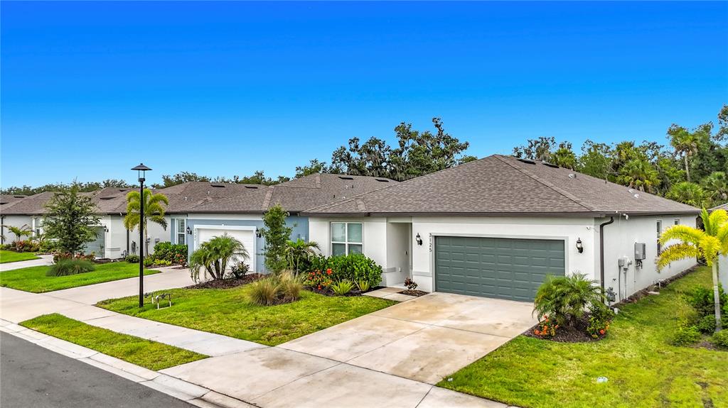 A single-story suburban house with a gray garage door and a concrete driveway — 3125 61ST TERRACE E, ELLENTON, FL