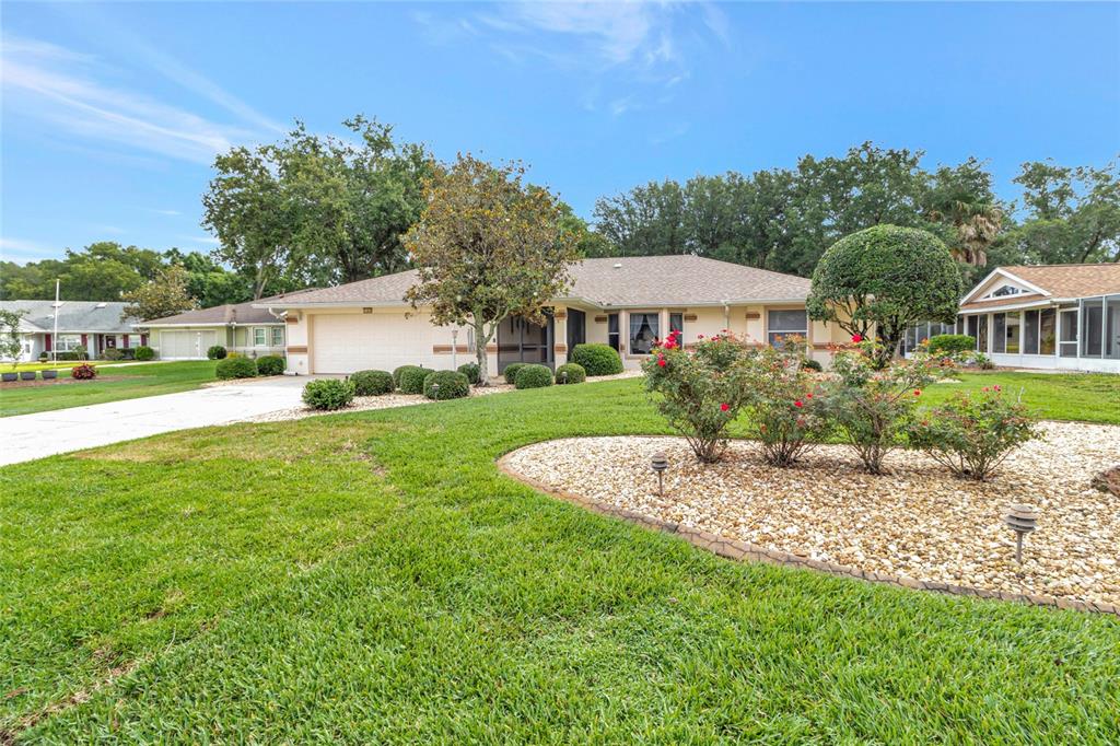 A single-story house with a beige exterior, a two-car garage, and a landscaped front yard — 21830 KING EDWARD COURT, LEESBURG, FL