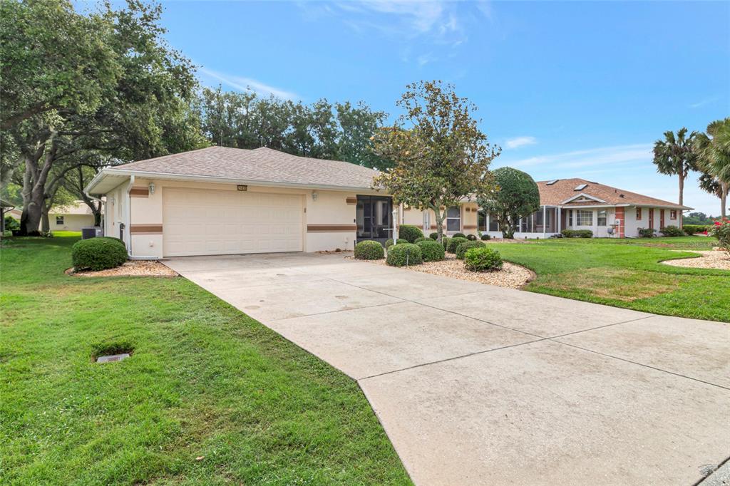 A single-story house with a two-car garage, a concrete driveway, and landscaped front yard — 21830 KING EDWARD COURT, LEESBURG, FL