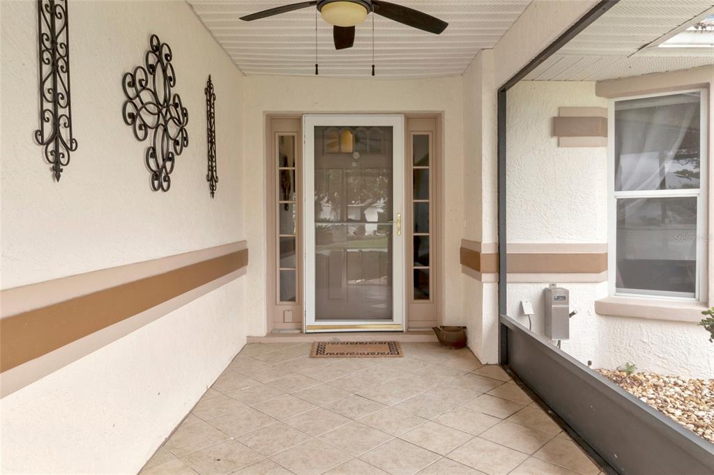 A covered porch features tiled flooring, a screen enclosure, and a front door with sidelights — 21830 KING EDWARD COURT, LEESBURG, FL