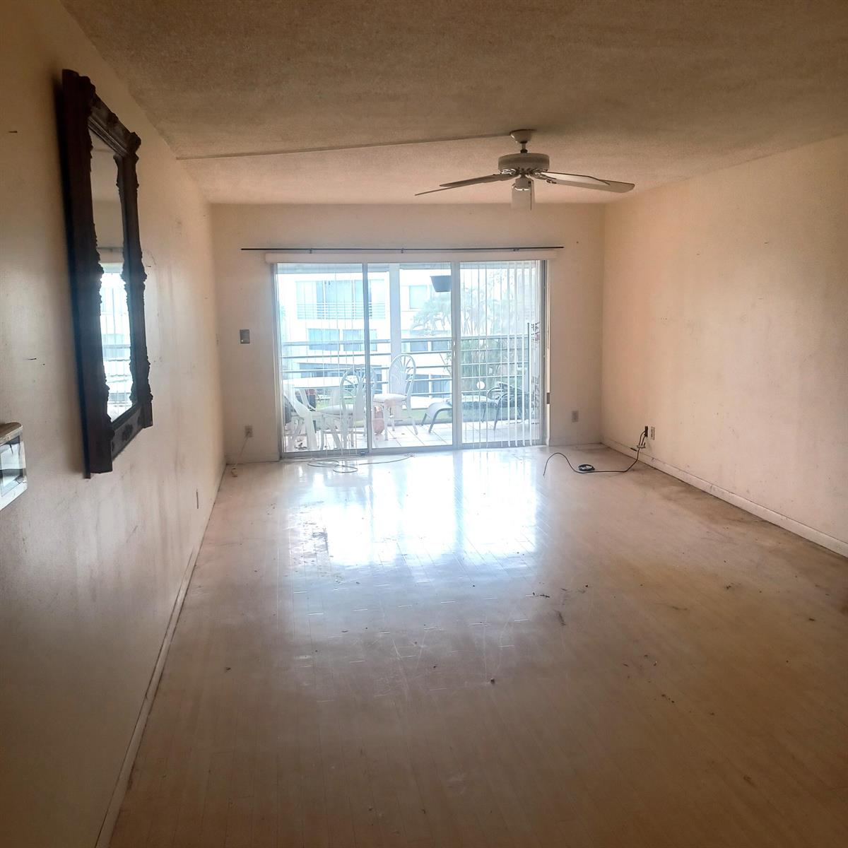 An empty living room features light-colored flooring, a ceiling fan, and a sliding glass door — 3186 Via Poinciana # 311, FL 33467, FL