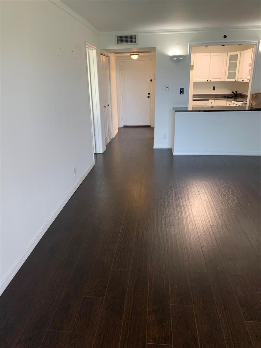 A view of an apartment interior featuring dark wood flooring, white walls, and a kitchen — 9355 SW 8th Street # 321, Boca Raton FL 33428, BOCA RATON, FL