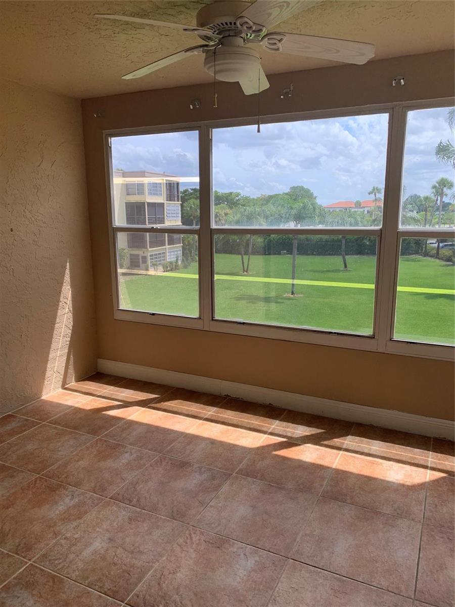 A sunroom with tile flooring, a ceiling fan, and large windows overlooking a grassy lawn — 9355 SW 8th Street # 321, Boca Raton FL 33428, BOCA RATON, FL
