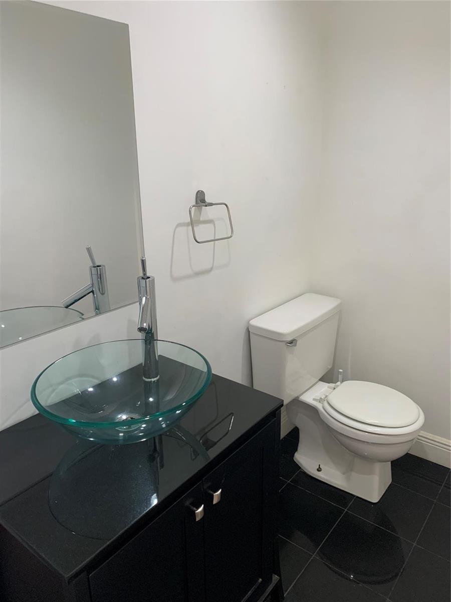 A bathroom features a glass vessel sink on a black vanity, a toilet, and tile flooring — 9355 SW 8th Street # 321, Boca Raton FL 33428, BOCA RATON, FL