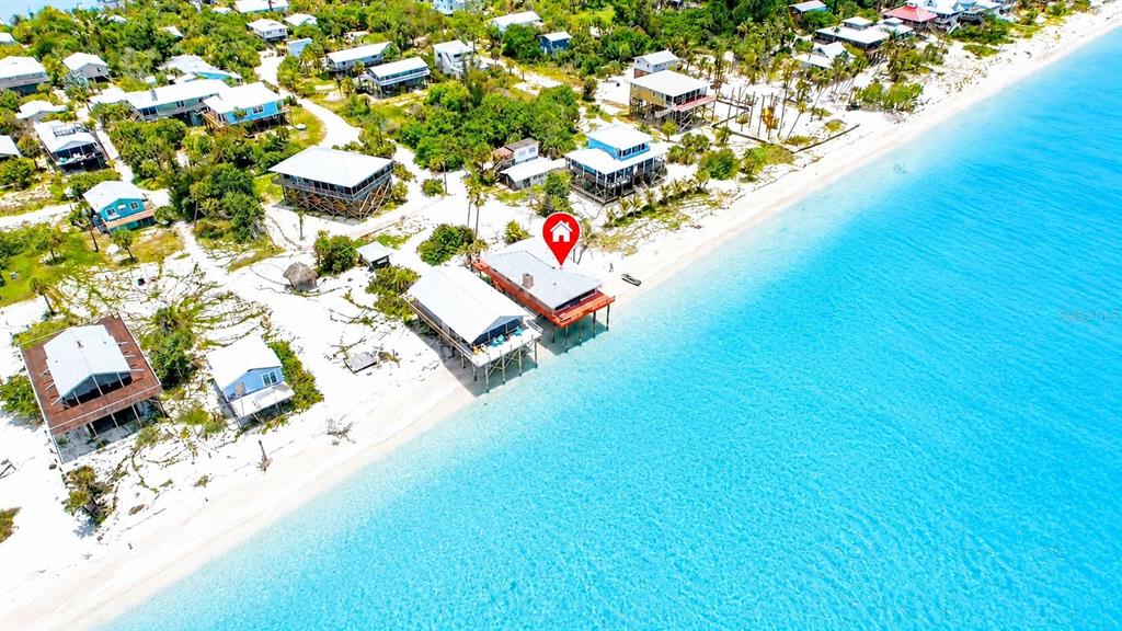 An aerial view shows several elevated beach houses along a sandy coastline by turquoise water — 8598 MARSH STREET, PLACIDA, FL