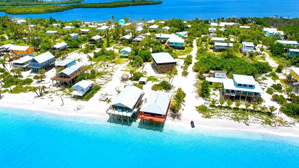 An aerial view shows a coastal community with stilt houses along a white sandy beach — 8598 MARSH STREET, PLACIDA, FL