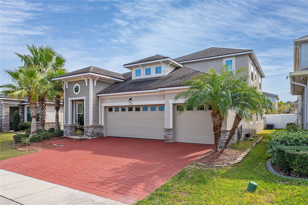 A two-story suburban house features a red brick driveway, a three-car garage, and palm trees — 3040 CARDILLINO WAY, KISSIMMEE, FL