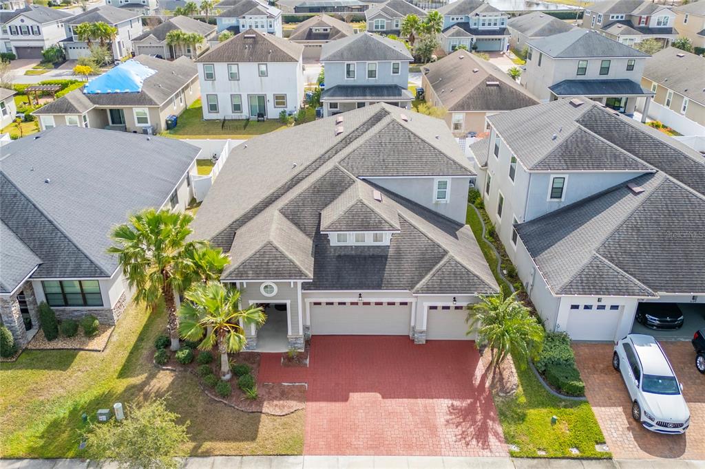 An aerial view shows a suburban house with a red brick driveway and palm trees — 3040 CARDILLINO WAY, KISSIMMEE, FL