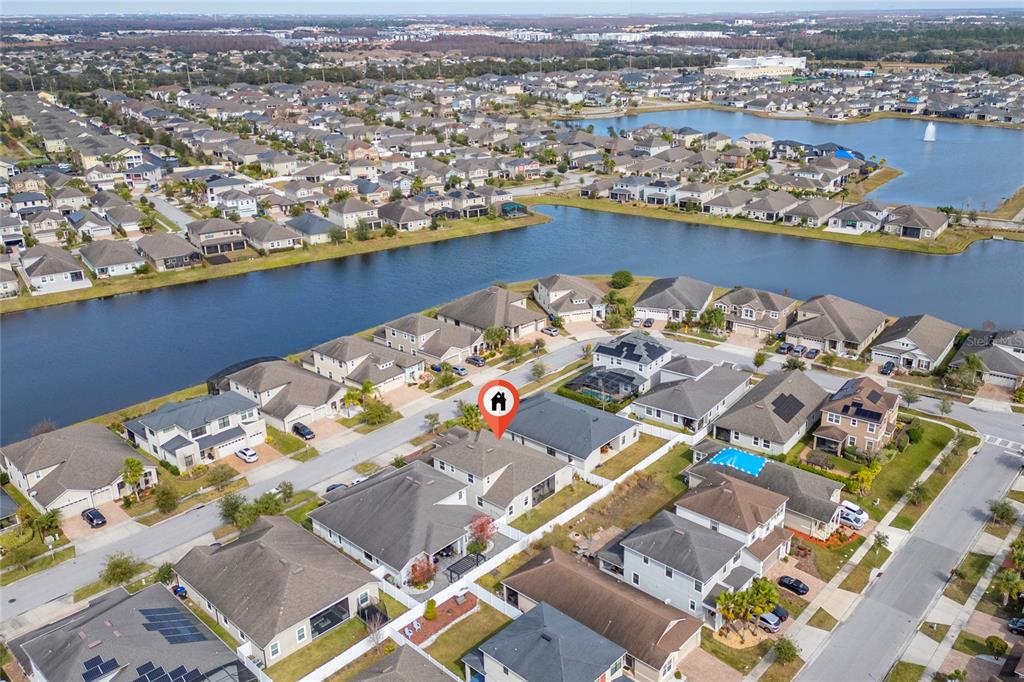 An aerial view shows a suburban neighborhood with houses surrounding a large retention pond — 3040 CARDILLINO WAY, KISSIMMEE, FL