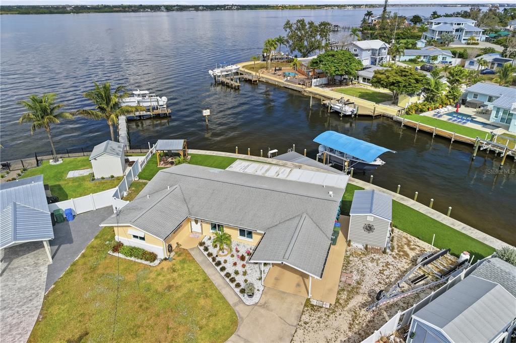 An aerial view shows a waterfront house with a boat dock and a blue canopy — 211 21ST STREET NE, BRADENTON, FL