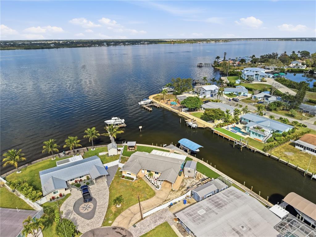 An aerial view shows waterfront houses with private docks along a canal and bay — 211 21ST STREET NE, BRADENTON, FL