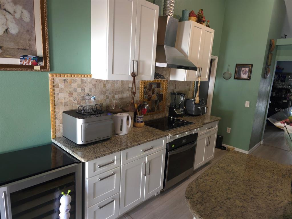A kitchen features white cabinets, granite countertops, a tile backsplash, and stainless steel appliances — 16 PERCH DRIVE, KISSIMMEE, FL