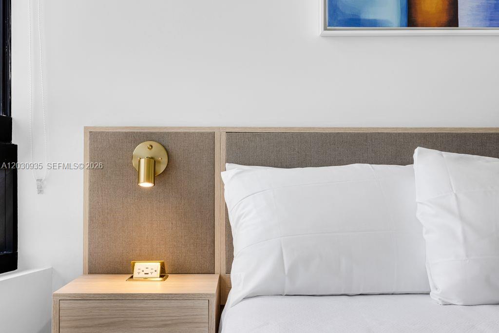 A bedroom features a light wood headboard with an integrated reading lamp and power outlet — 225 N Miami Ave # 3507, Miami FL 33128, MIAMI, FL