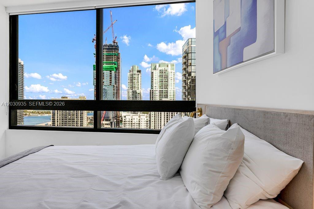 A bedroom features a large window with a view of city skyscrapers and water — 225 N Miami Ave # 3507, Miami FL 33128, MIAMI, FL