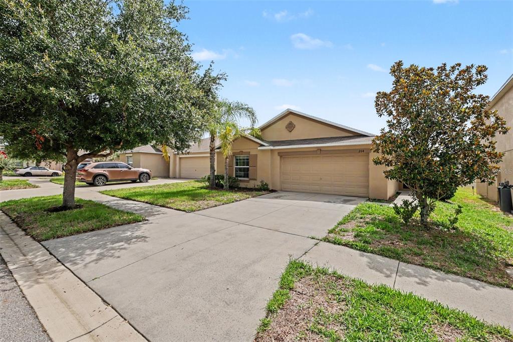 A single-story house with a beige stucco exterior, a two-car garage, and a concrete driveway — 204 ENGLISH CHANNEL PLACE, DOVER, FL