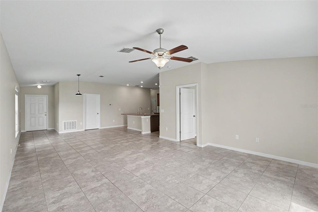 An open-concept living area features light-colored tile flooring, a ceiling fan, and a kitchen island — 204 ENGLISH CHANNEL PLACE, DOVER, FL