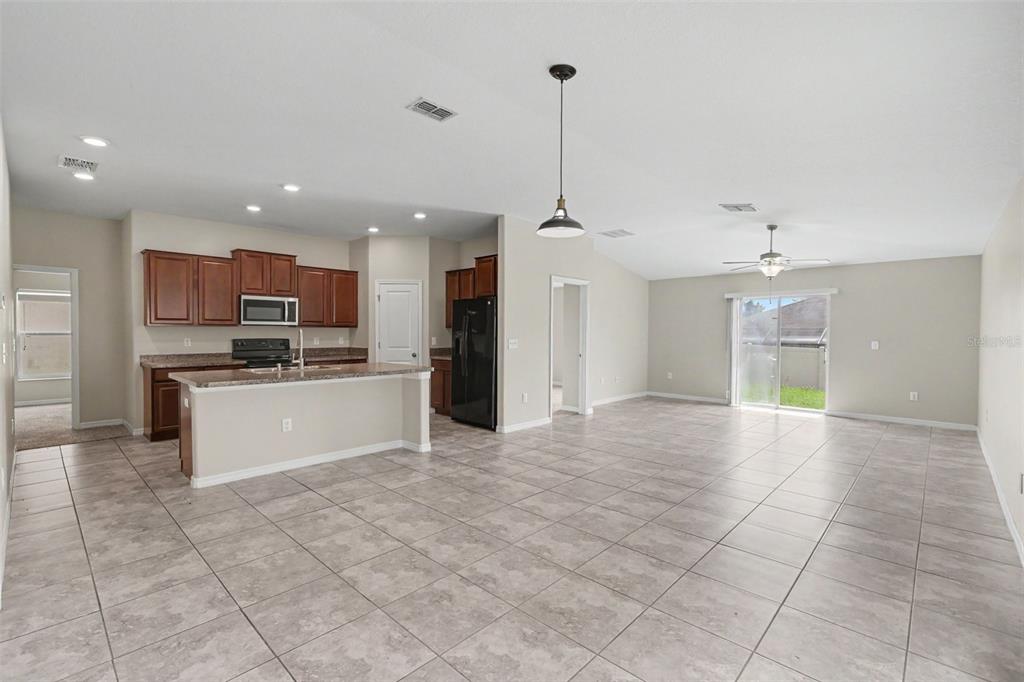 An open-concept kitchen and living area with tile flooring, dark wood cabinets, and sliding doors — 204 ENGLISH CHANNEL PLACE, DOVER, FL