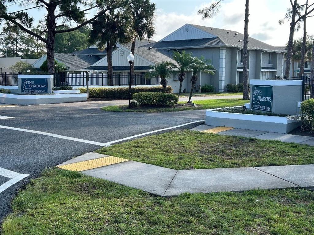 The entrance to Pine Shadows Condominiums features two matching signs and a paved driveway — 4452 PINEBARK AVENUE UNIT 56-3, ORLANDO, FL