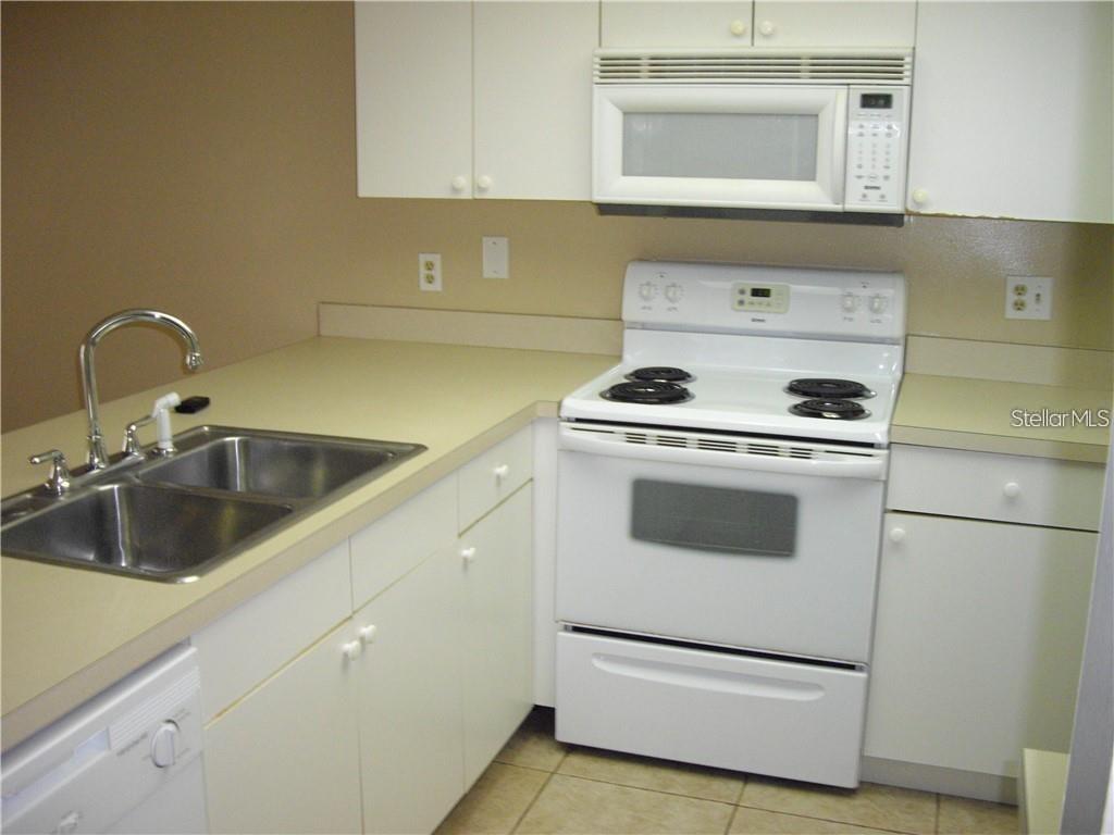 A kitchen features white cabinets, white appliances, a double sink, and beige countertops — 4452 PINEBARK AVENUE UNIT 56-3, ORLANDO, FL