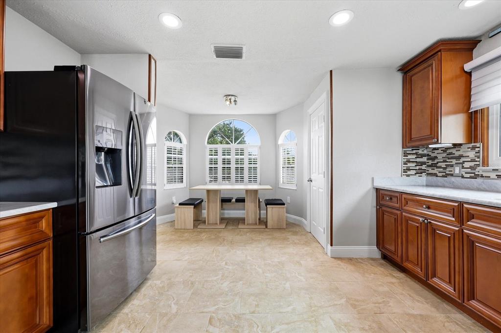 A kitchen with wood cabinets, stainless steel appliances, tile floors, and a breakfast nook area — 610 ISLAND WAY UNIT 201, CLEARWATER BEACH, FL