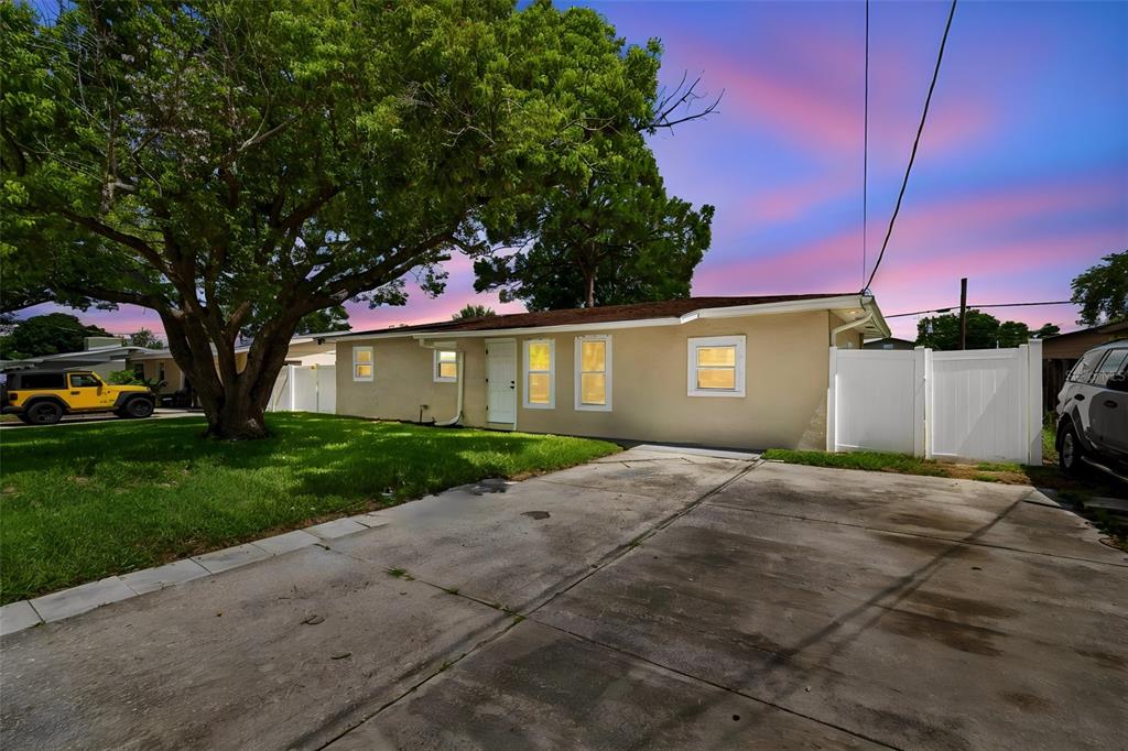 A single-story house with a concrete driveway, a large tree, and a white fence — 4417 W FAIRVIEW HEIGHTS, TAMPA, FL