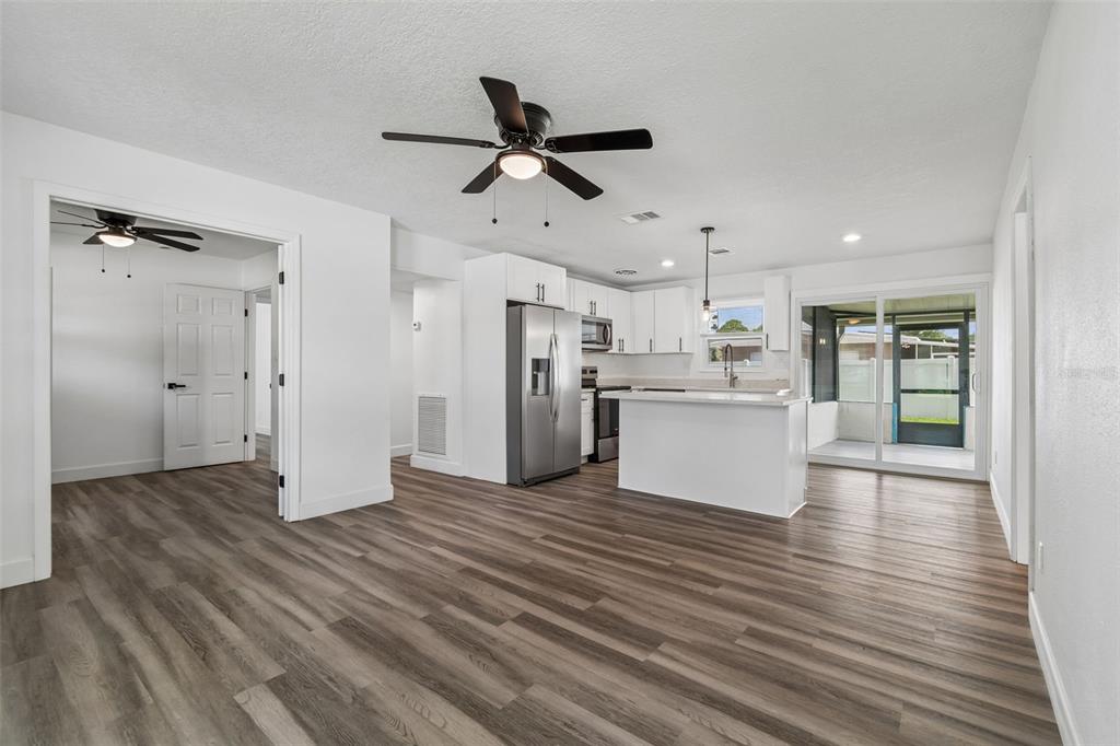 An open-concept kitchen and living area features white cabinets, stainless appliances, and wood-look flooring — 4417 W FAIRVIEW HEIGHTS, TAMPA, FL