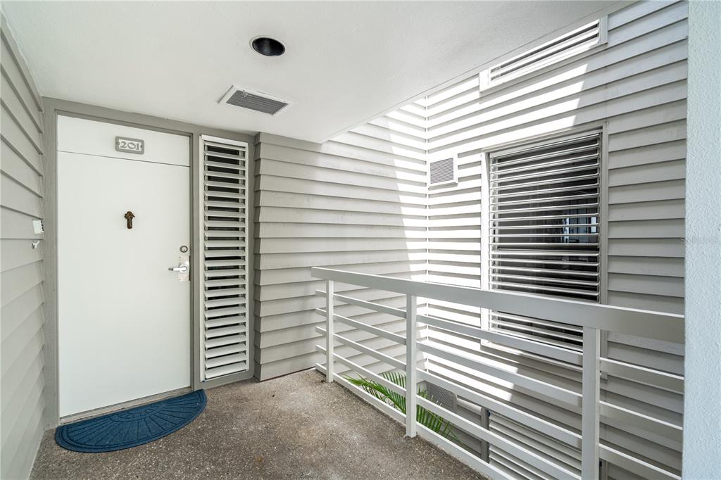 An exterior view of a building entrance with a white door labeled 201 and railings — 615 DREAM ISLAND PLACE UNIT 201, LONGBOAT KEY, FL