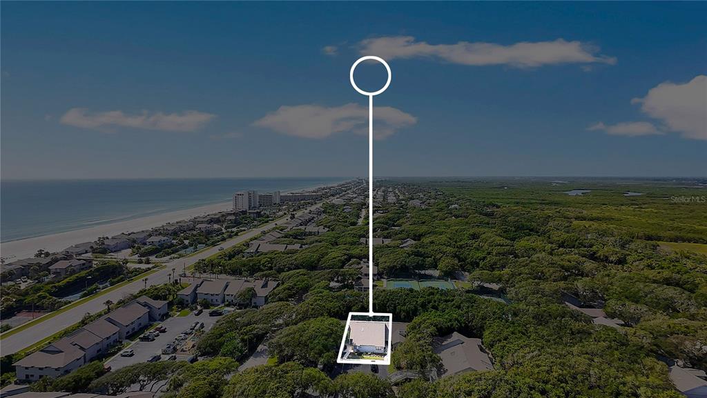 An aerial view shows a house surrounded by trees near a beach and ocean — 4360 SEA MIST DRIVE, NEW SMYRNA BEACH, FL