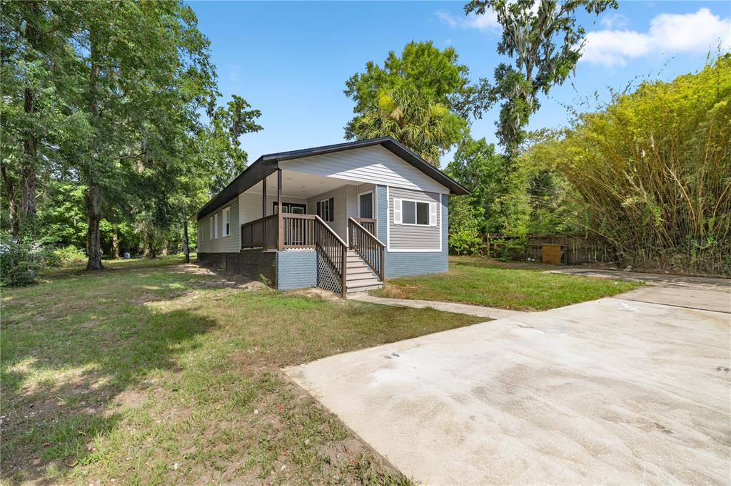 A single-story house with gray siding, a brick base, and a covered front porch — 1127 SW 140TH AVENUE, OCALA, FL