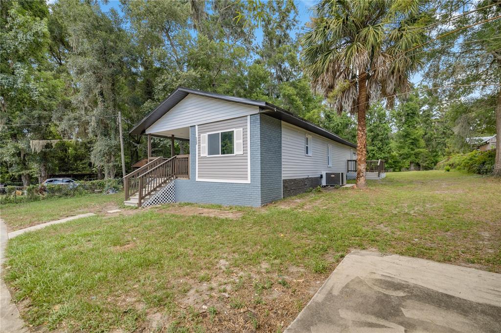 A single-story house with gray siding and brick accents features a wooden front porch — 1127 SW 140TH AVENUE, OCALA, FL